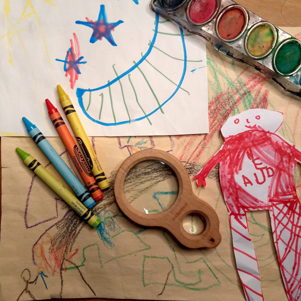 Kid's drawings, crayons, and magnifying glass.