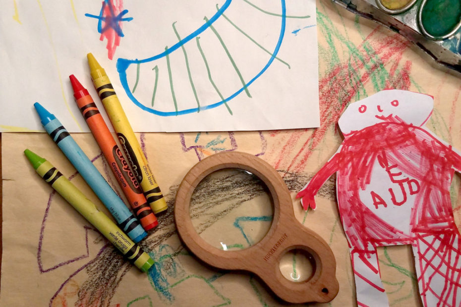 Kid's drawings, crayons, and magnifying glass.